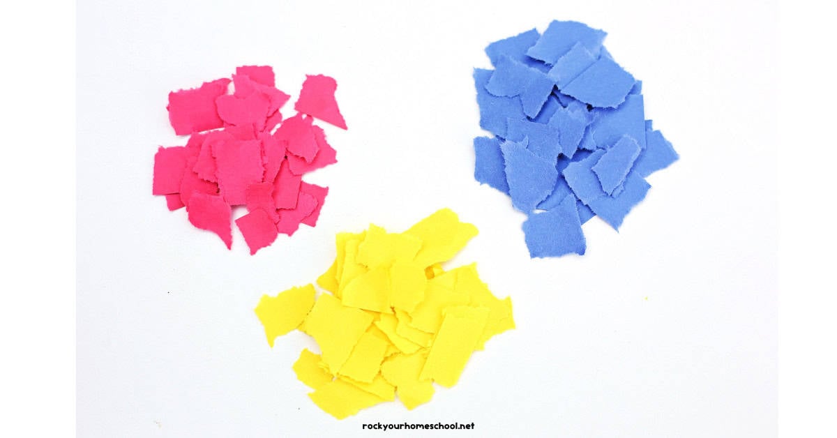 Piles of red, yellow, and blue construction paper in torn squares.