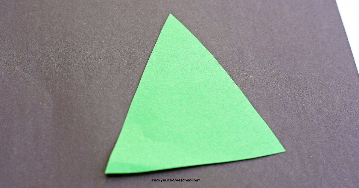 Green paper triangle on black construction paper. 