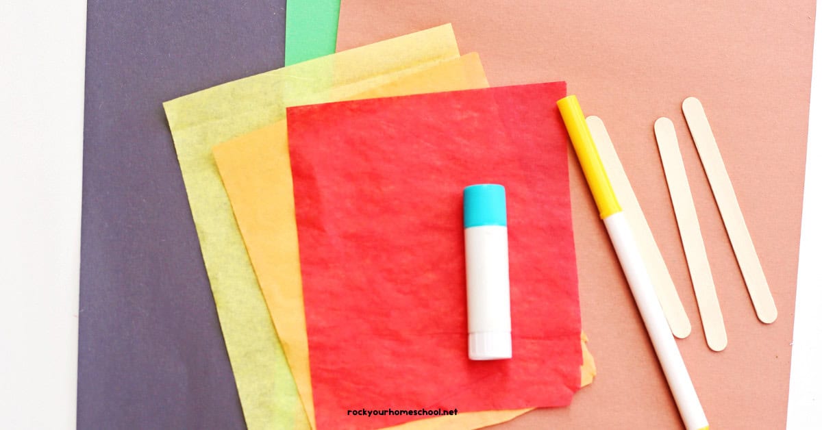 Black, green, and brown construction paper with red, orange, and yellow tissue paper, glue stick, marker, and popsicle sticks.