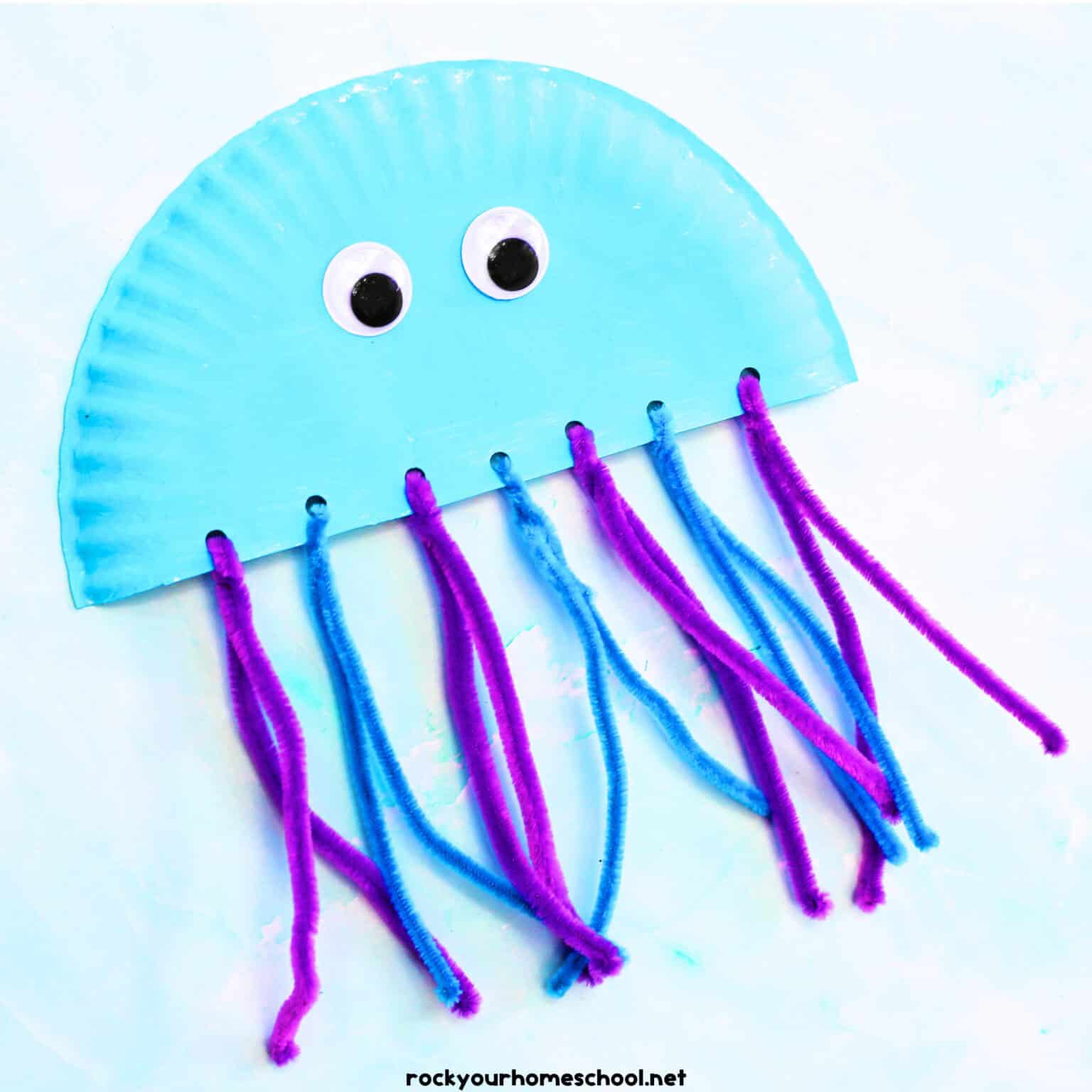Example of paper plate jellyfish craft with blue and purple pipe cleaners and googly eyes.
