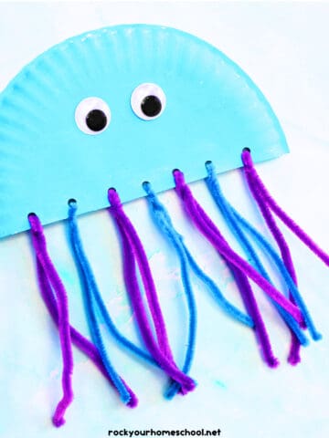 Example of paper plate jellyfish craft with blue and purple pipe cleaners and googly eyes.
