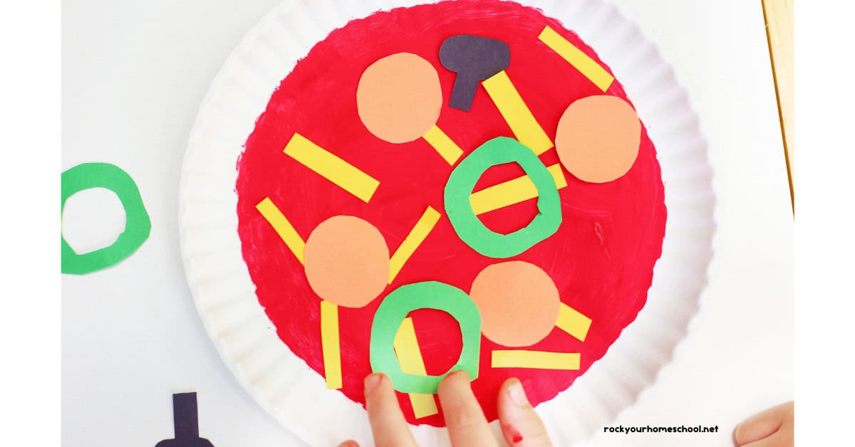 Child adding green circle paper pizza topping to paper plate pizza craft.
