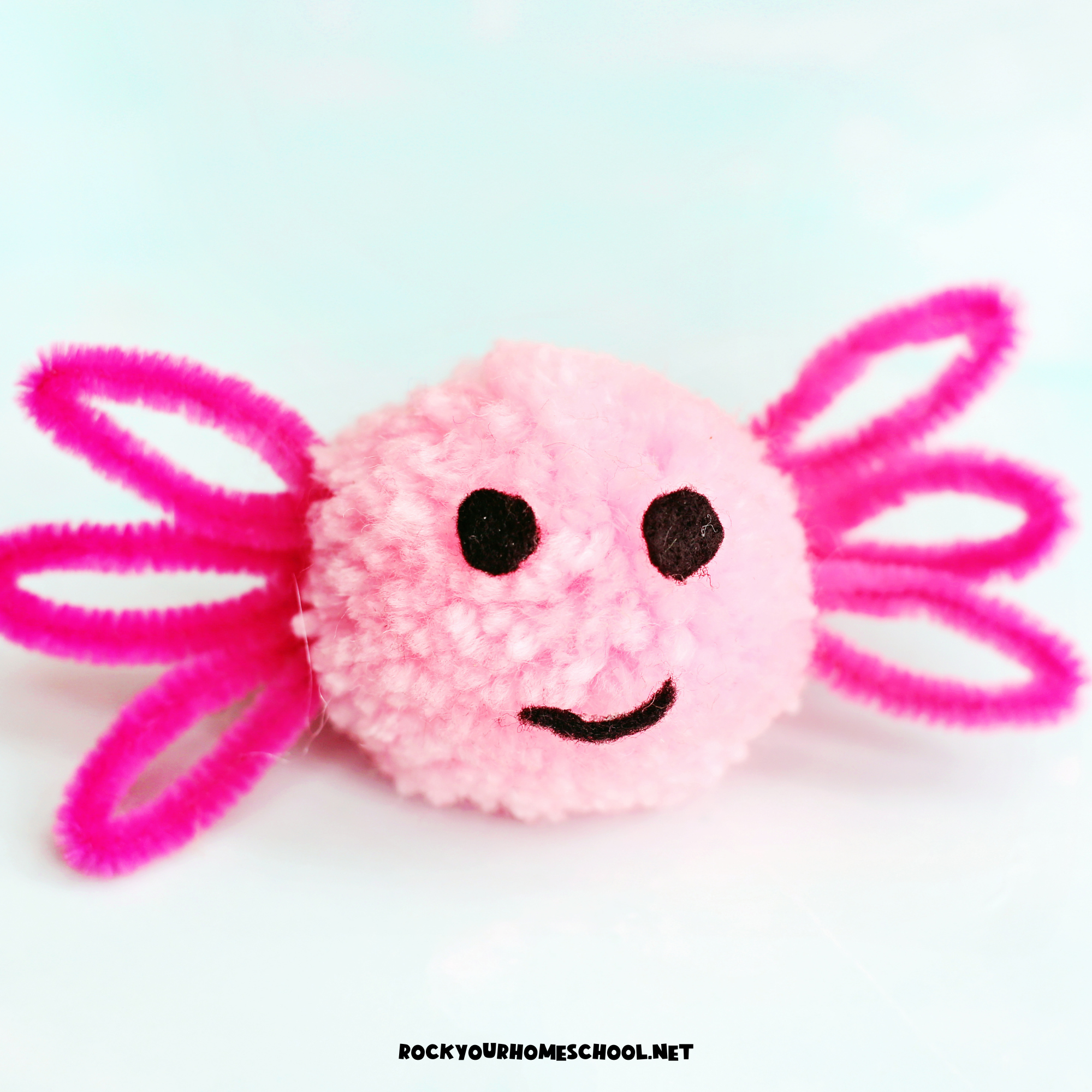 Example of easy axolotl craft for kids made with pink pom pom, pipe cleaners, and black felt.