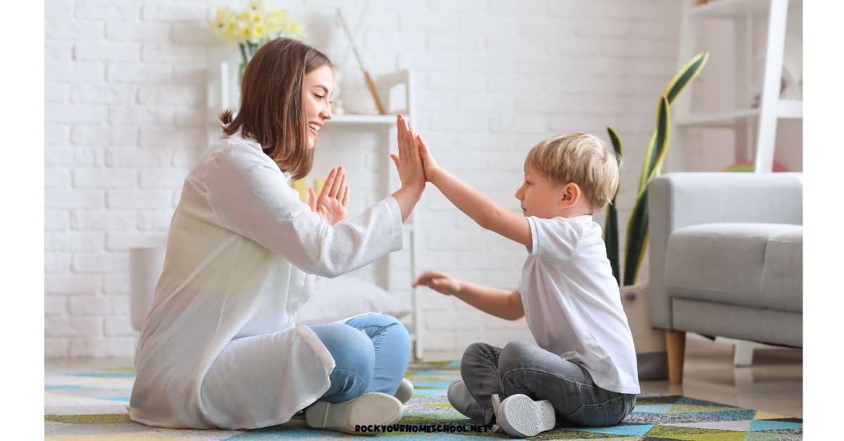 Mother and son sitting on rug and clapping hands for first day of preschool at home fun.