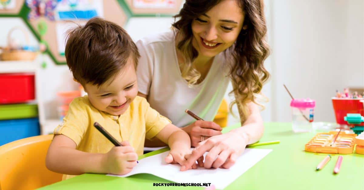 Mother and son smiling as they work on a first day of homeschool preschool activity with watercolor paints and color pencils.