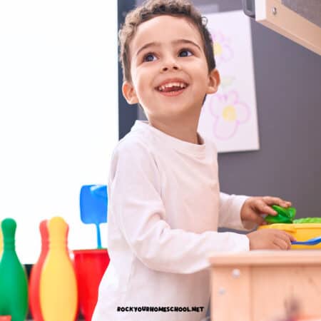 Preschool boy smiling as he plays at toy stove.