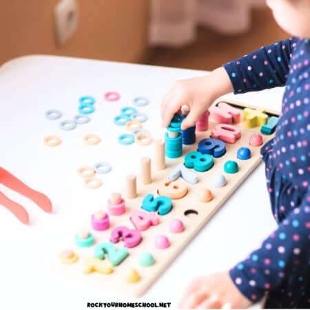Preschool girl using wood puzzle for number preschool activities.