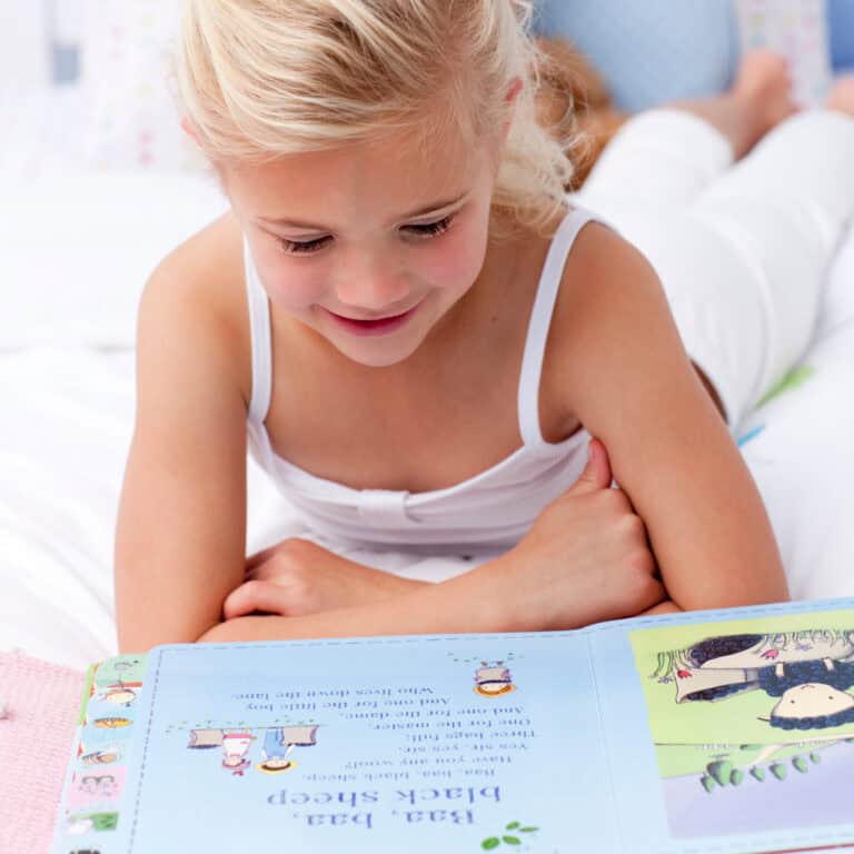 Girl reading Baa Baa Black Sheep in nursery rhyme book.
