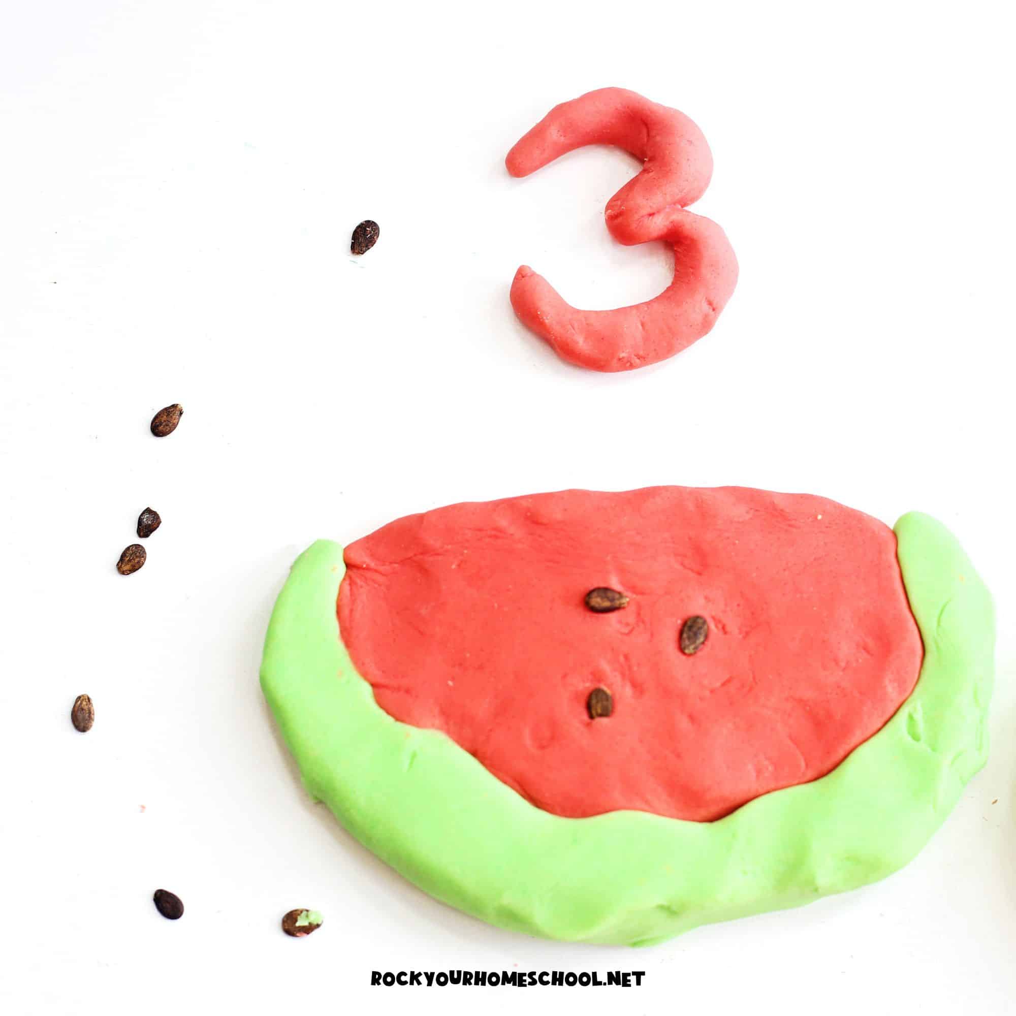 Homemade watermelon playdough in red and light green with watermelon seeds.