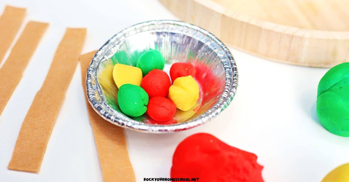 Red, yellow, and green playdough balls in mini pie pan with brown felt strips.