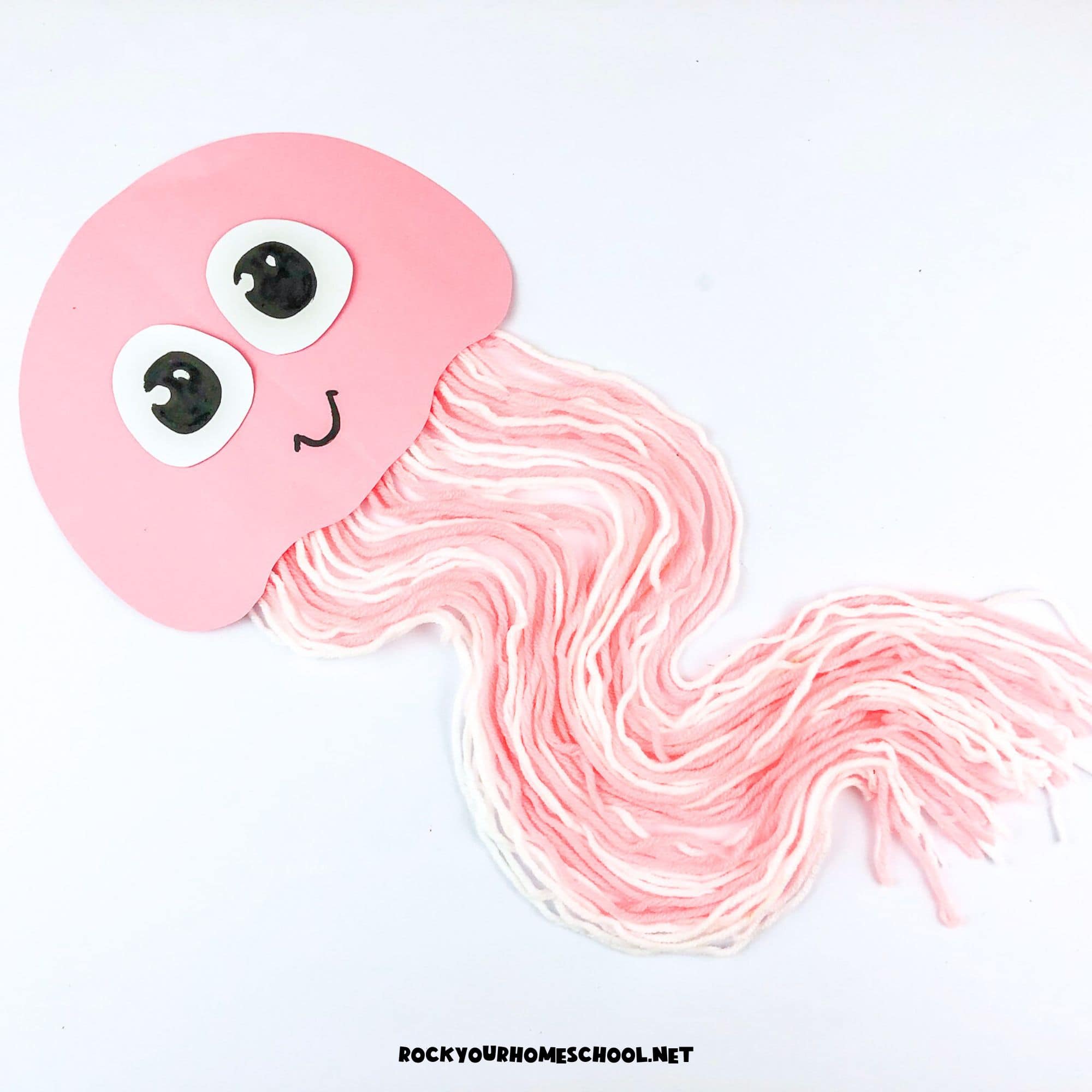 Example of pink and white easy jellyfish craft for kids using paper and yarn.
