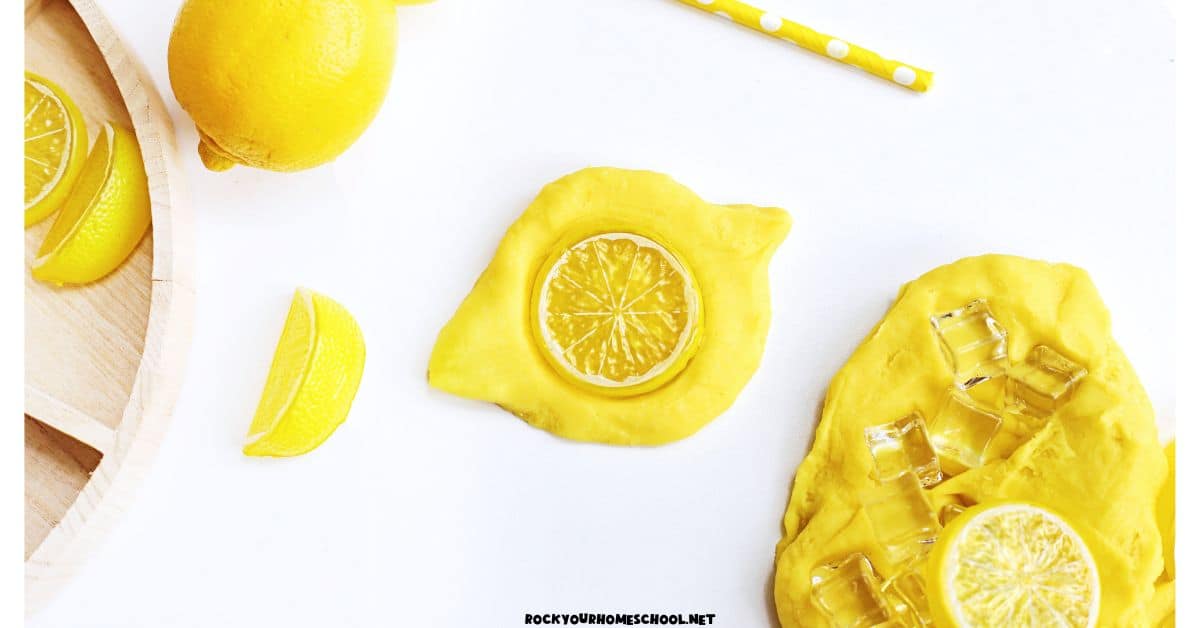 Yellow lemon playdough with plastic lemon slices, plastic play ice, and yellow paper straws.