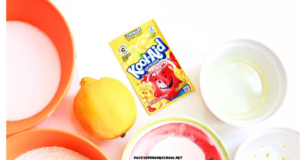 Supplies for lemon playdough with lemon, Kool-Aid lemonade pack, oil, flour, salt, cream of tartar.