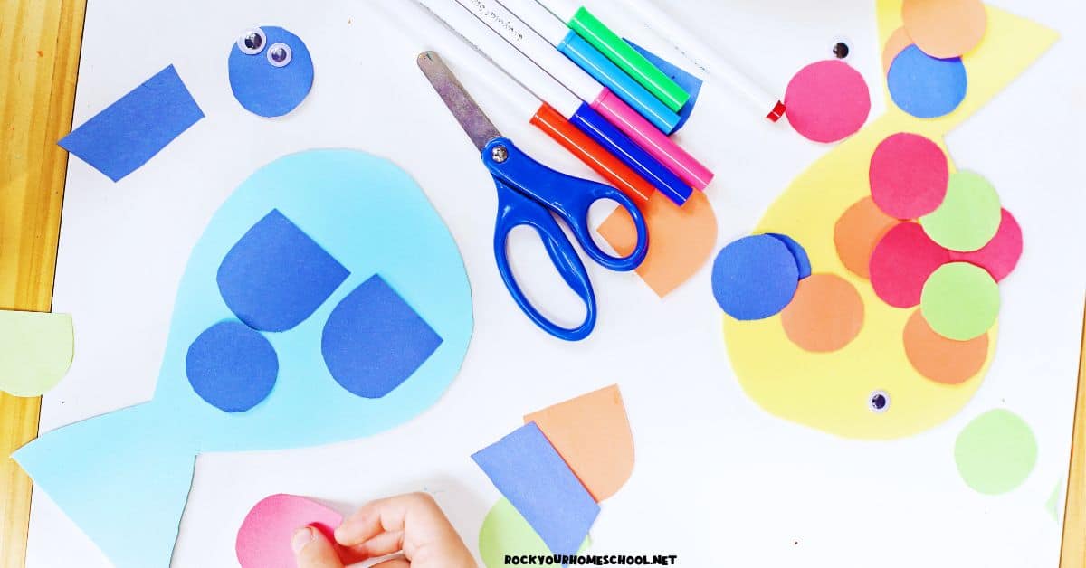 Child making easy paper fish craft with pieces of construction paper, scissors, googly eyes, and markers.