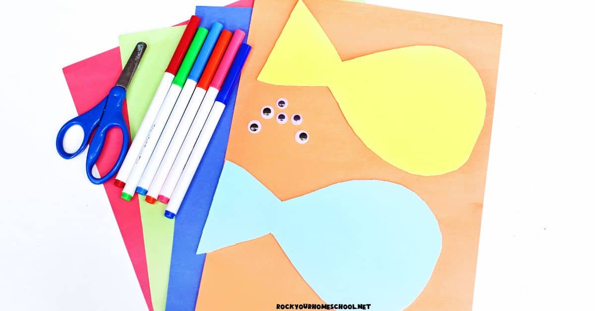 Construction paper in red, green, blue, and orange with yellow and light blue fish paper shapes, googly eyes, markers, and scissors.