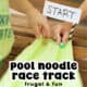 Two boys using marbles on green pool noodle race track.