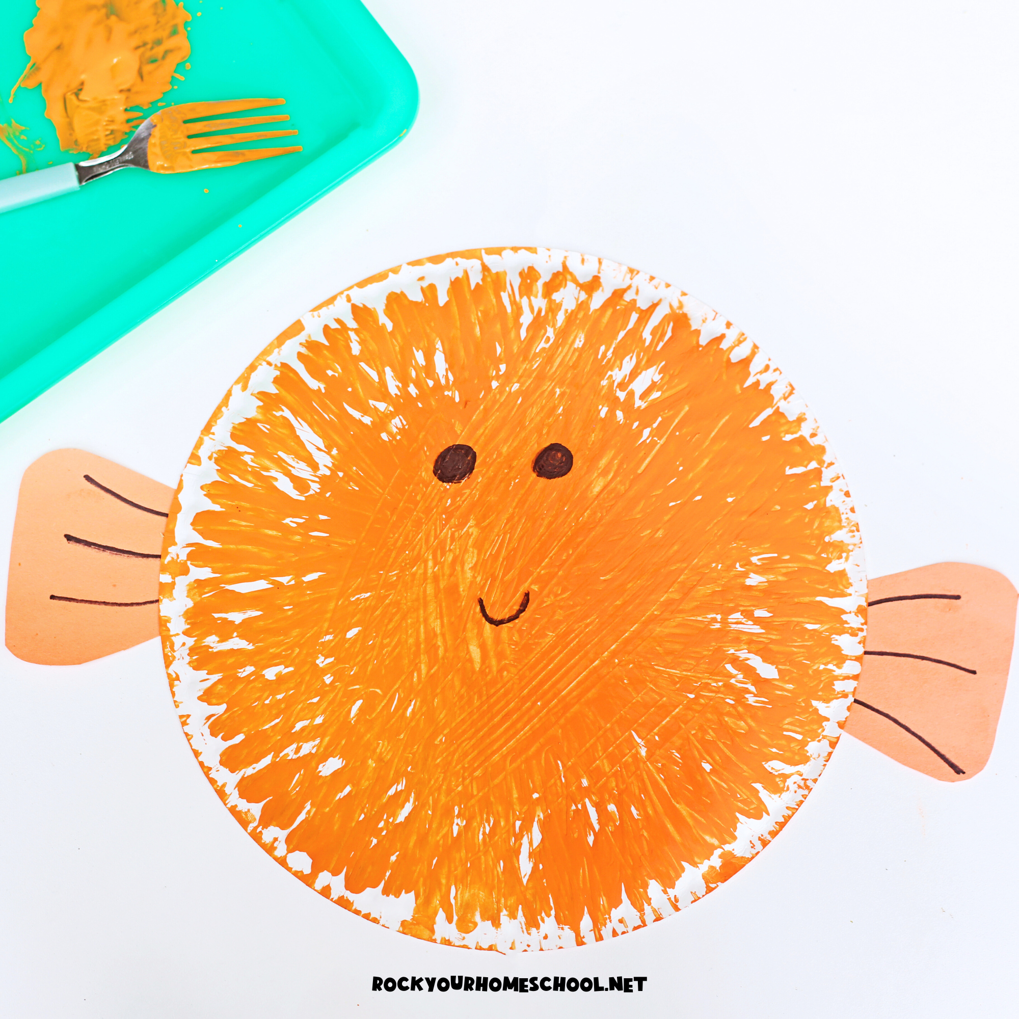 Example of orange fork-painted puffer fish paper plate craft for kids.