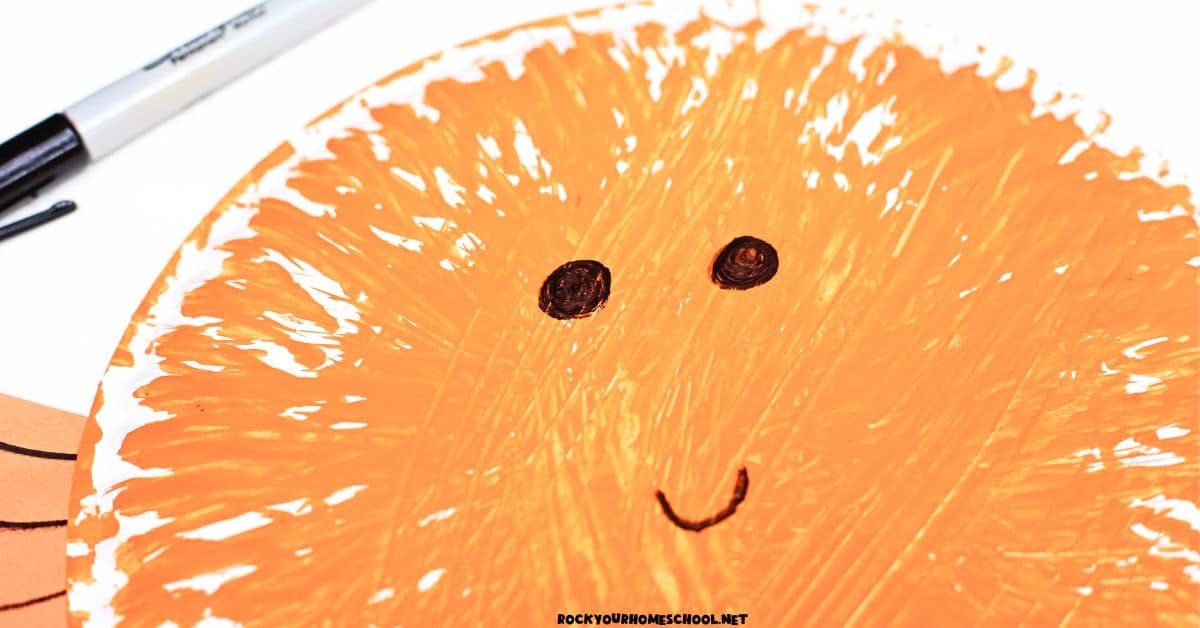 Black marker used to draw smiley face on fork-painted puffer fish paper plate.