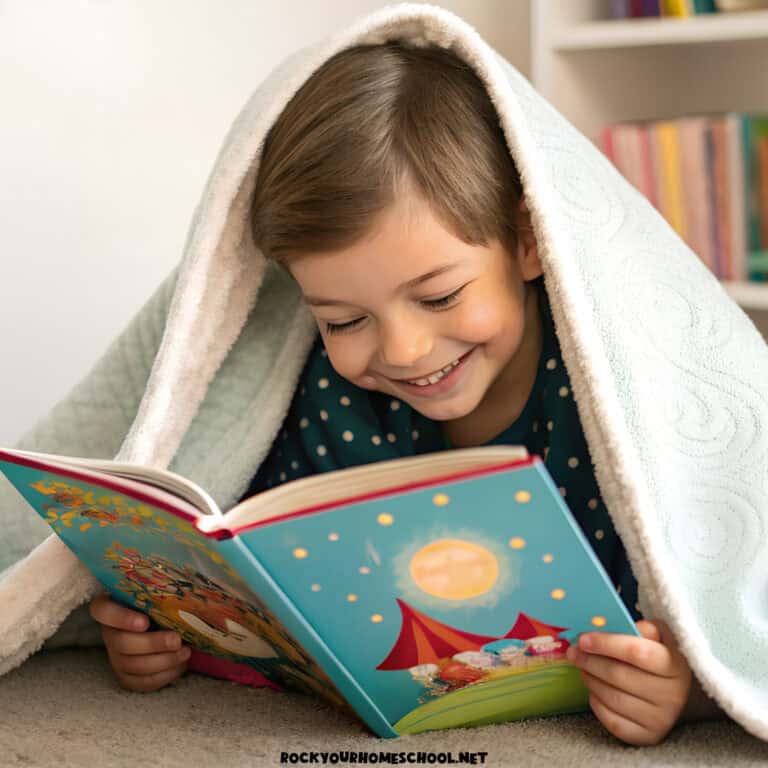 Smiling young child reading a colorful book under a cozy blanket during quiet time at home.