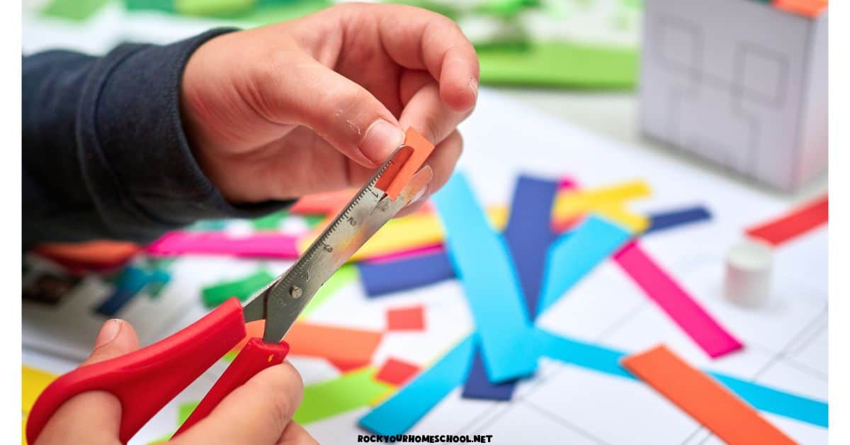 Child using scissors to cut colorful paper strips for paper house craft for an enjoyable quiet time activity for kids.