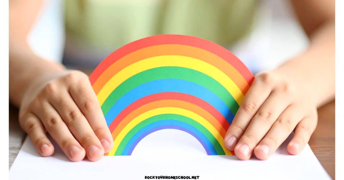 Child holding paper rainbow for a mindful and calming quiet activity.