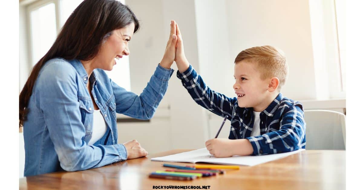 Smiling mother and son giving each other high five while coloring.