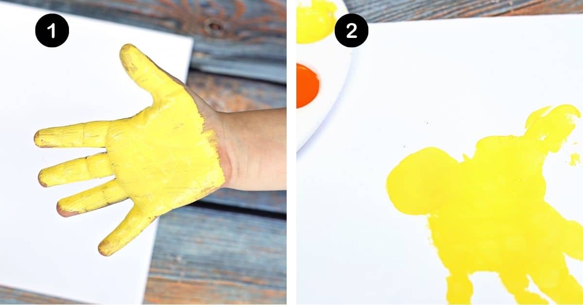 Child with yellow paint on hand and handprint on white paper.