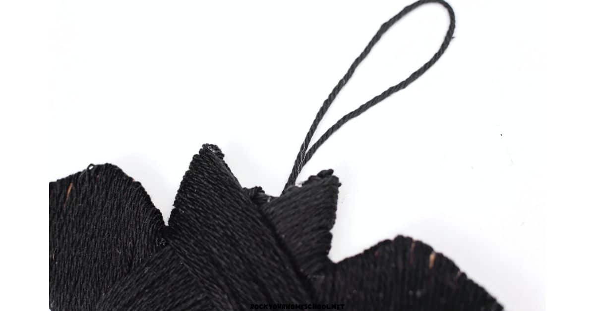 Easy bat craft made with cardboard and black yarn and yarn loop at top to be used as hanger.