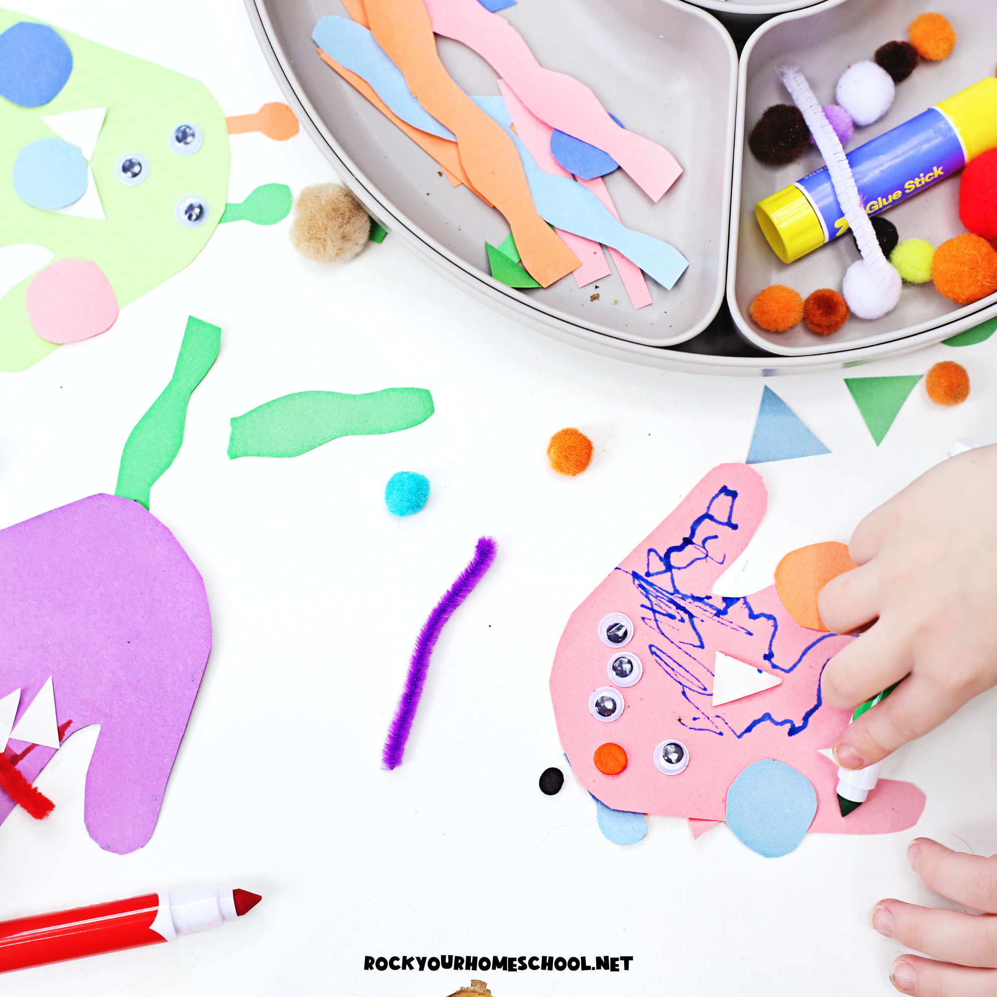 Child working on monster handprint craft with construction paper, marker, googly eyes, pipe cleaner pieces, and more.