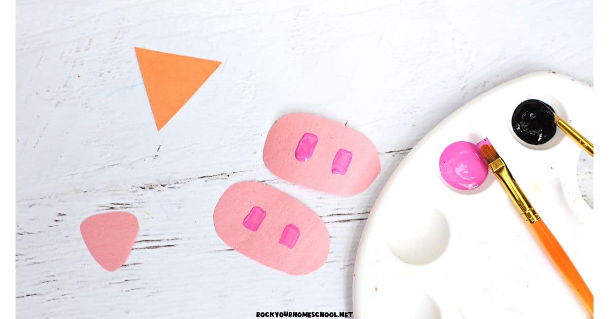 Orange paper triangle, pink triangle, 2 pink ovals, and pink and black paints.