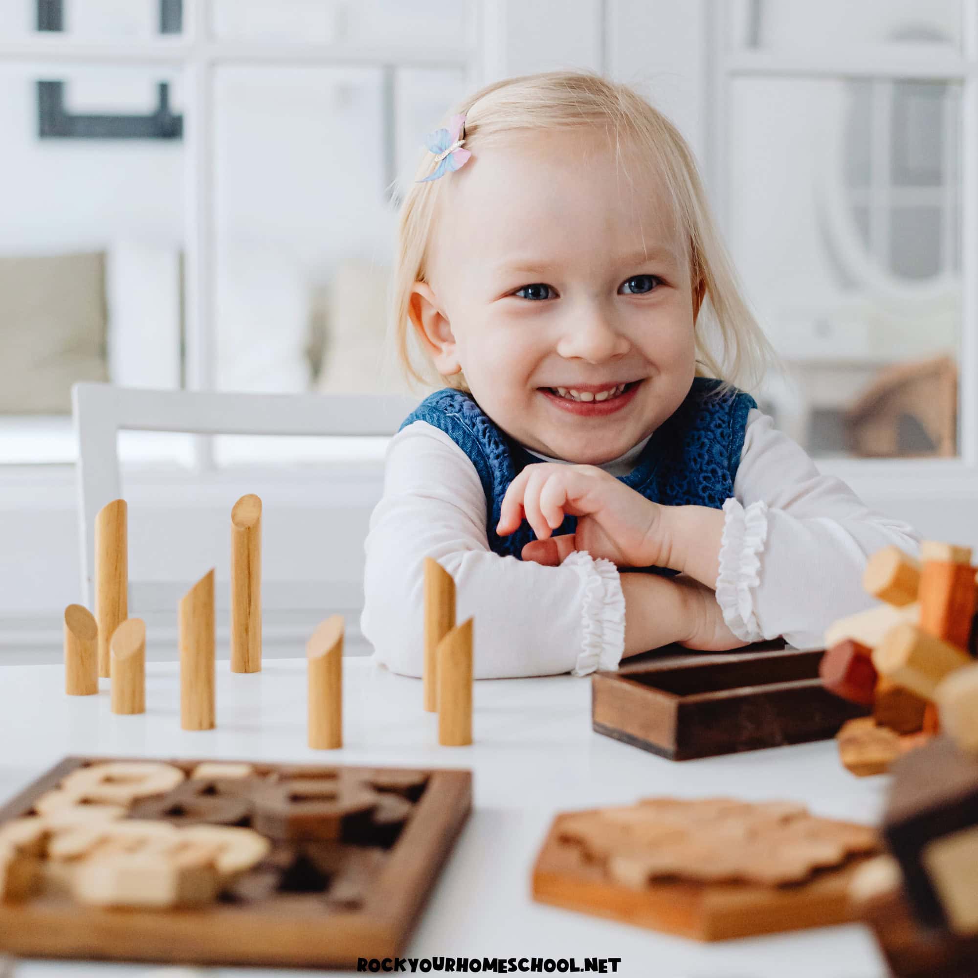 Young girl smiling as she uses wood blocks for quiet time activities.