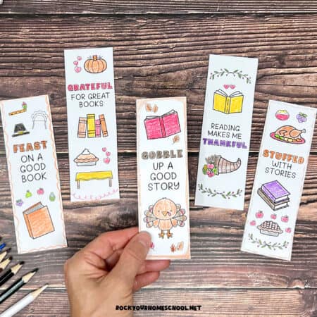 Woman holding examples of free printable Thanksgiving bookmarks to color.