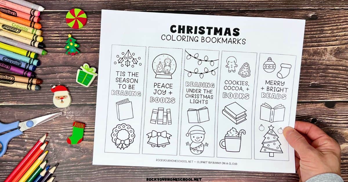 Woman holding page of printable Christmas coloring bookmarks.