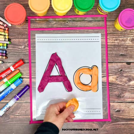 Woman holding orange playdough with letter Aa free printable alphabet playdough mat.