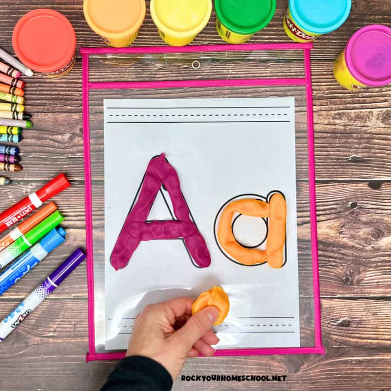 Woman holding orange playdough with letter Aa free printable alphabet playdough mat.