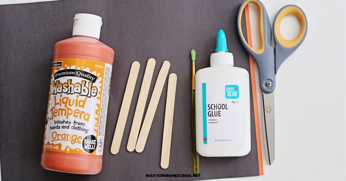 Black and orange construction paper, orange paint, wood popsicle sticks, paint brush, glue, and scissors.