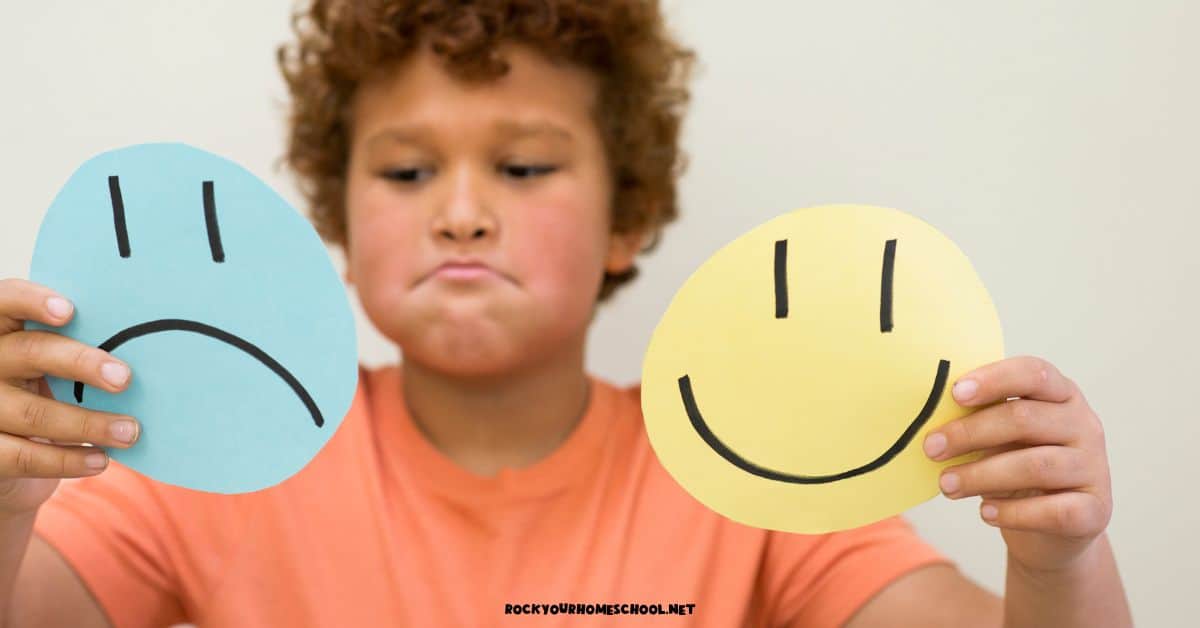 Child holding paper circles with emotional expressions of frown and smile for social-emotional learning.