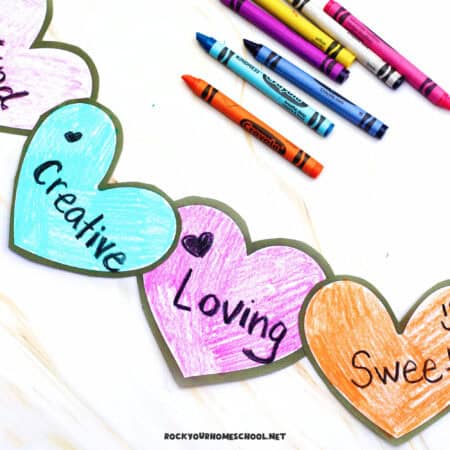 Paper hearts colored with crayons for this simple kindness craft for kids.