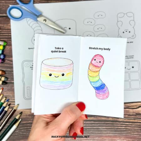 Woman holding free printable coping skills activity that is a mini coloring book featuring cute candy themes.