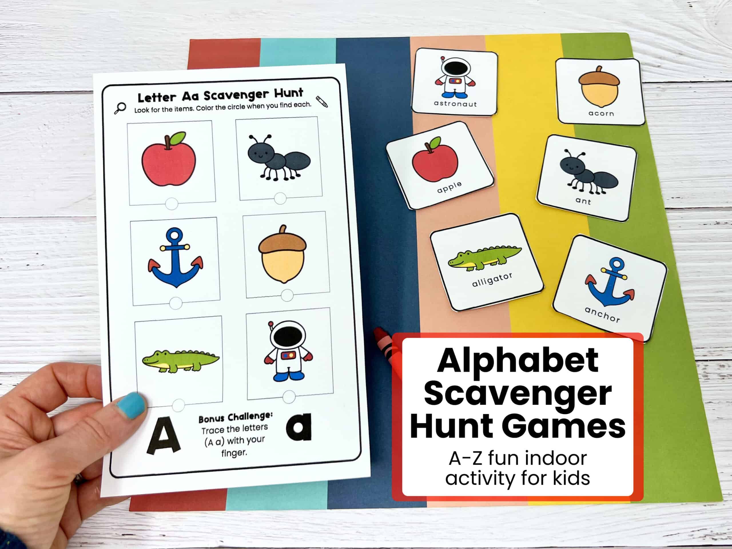 Woman holding alphabet scavenger hunt card featuring Aa with cards in background.