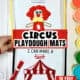 Woman holding examples of free printable circus playdough mats for kids featuring clown and big top tent.