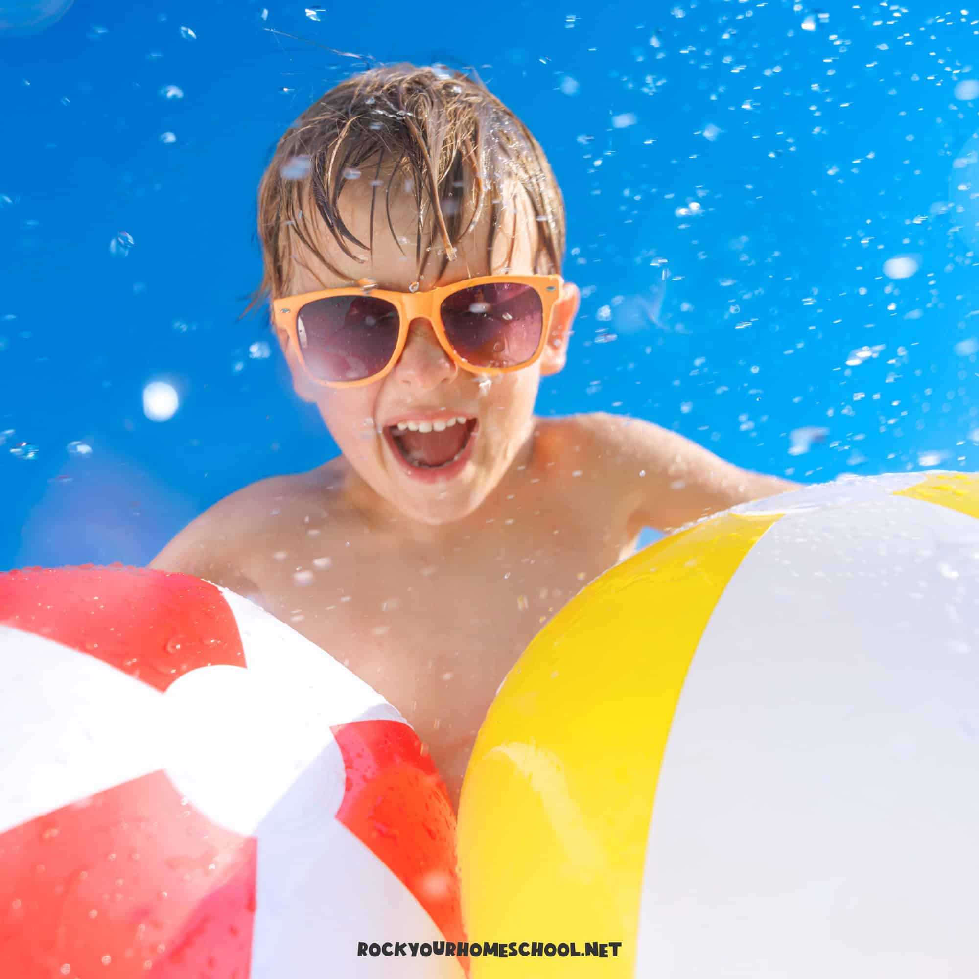 Young boy smiling as he wears sunglasses and holds beach balls to feature preschool summer themes.