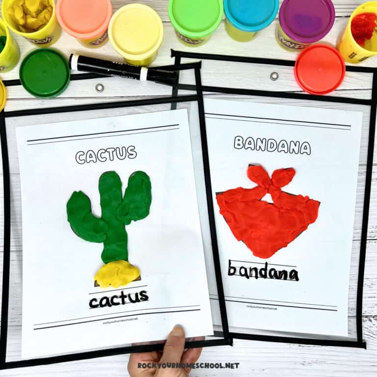 Woman holding two examples of wild west playdough mats featuring cactus and bandana.