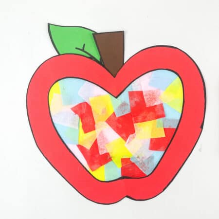 Apple suncatcher craft made with construction paper, tissue paper, and tape.
