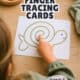 Young girl using her finger to trace a green line of a turtle shape to show how finger tracing cards for kids work as calm down tools.