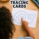 Young girl using her finger to trace a continuous blue line in a whale shape to show how finger tracing cards for kids work as calm down tools.