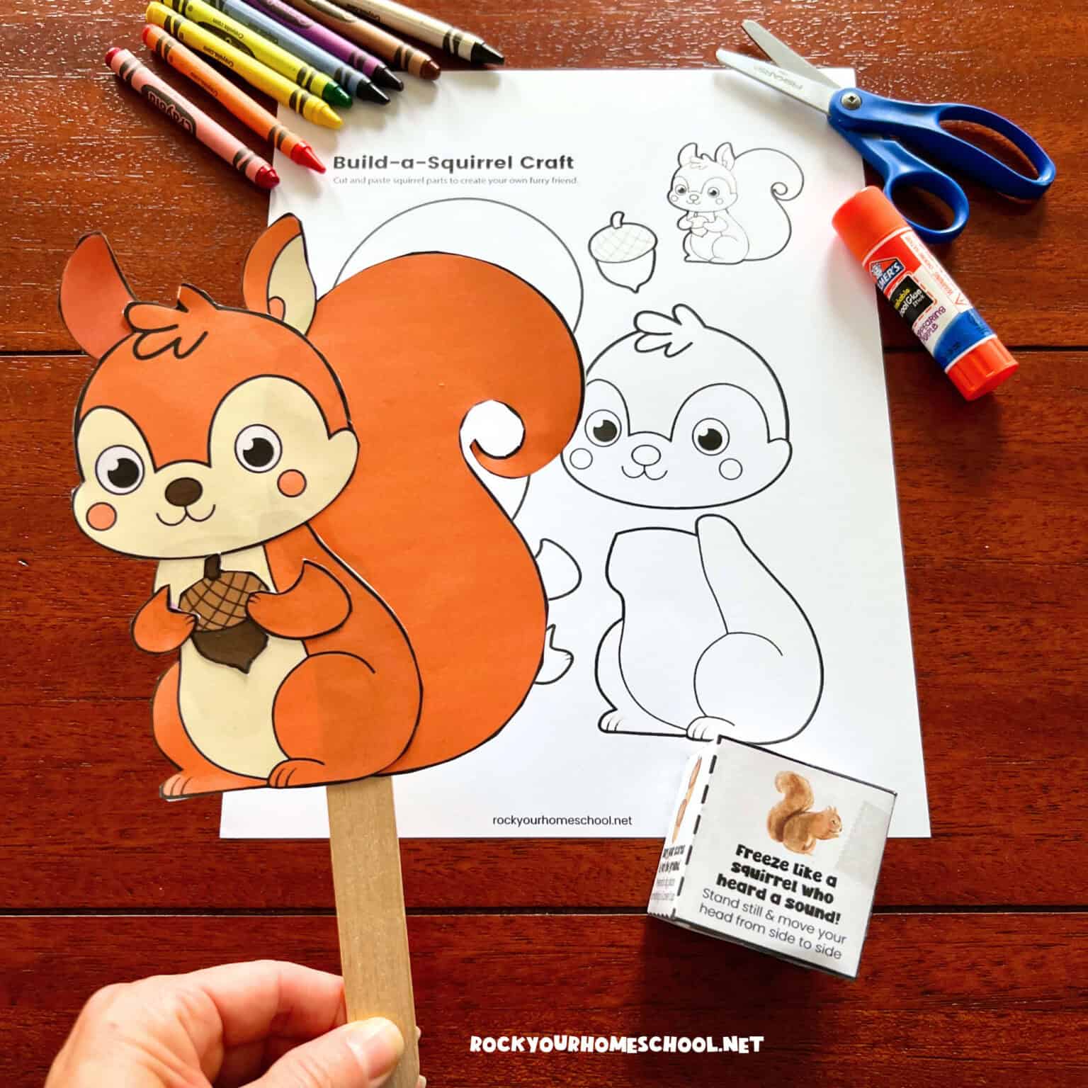 Woman holding printable squirrel craft on a wood craft stick and squirrel movement dice game.